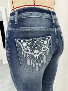 Dettaglio ricamo floreale bianco sulla tasca posteriore di jeans a zampa d'elefante
