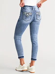 Detailed view of women's blue skinny jeans with floral embroidery on back pockets.