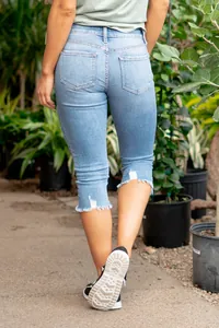 Vista trasera de pantalones capri vaqueros ajustados con dobladillo deshilachado.