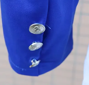 Detailansicht eines blauen Blazer-Ärmels mit dekorativen silbernen Löwenkopfknöpfen