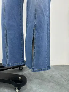 Dettaglio di jeans slim da donna con spacchi anteriori sull'orlo e cuciture gialle