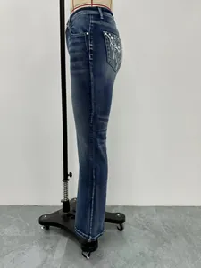 Vista laterale dei jeans a zampa blu da donna con elegante ricamo floreale bianco sulla tasca