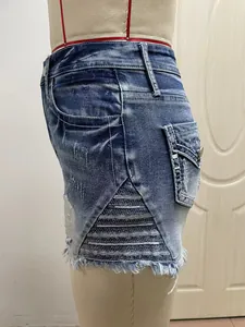 Detailopname van distressed denim shorts met mesh-borduurwerk en gerafelde randen