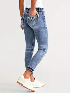 Back view of women's blue slim fit skinny jeans with floral embroidered pockets and stretch denim