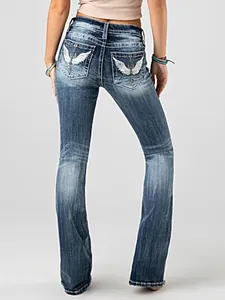 Close-up of women's washed denim jeans with intricate wing embroidery on back pockets