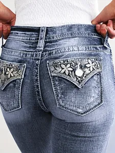 Close-up detail of intricate floral embroidery on the back pockets of slim-fit denim jeans