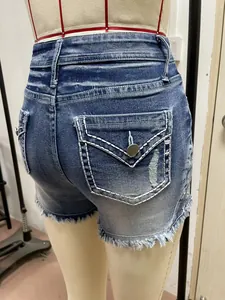 Detail van distressed denim shorts voor dames met witte stiksels op de achterzak en franjes.