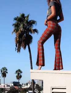 Pantalon évasé à carreaux orange et noir, coupe ajustée, présenté en extérieur.
