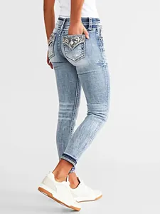 Detail view of women's light blue skinny jeans with floral back pocket embroidery