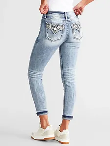 Detailed back view of women's light blue slim-fit jeans featuring floral pocket embroidery