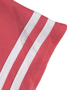 Macro view of coral pink sportswear fabric showing premium white triple stripes detail