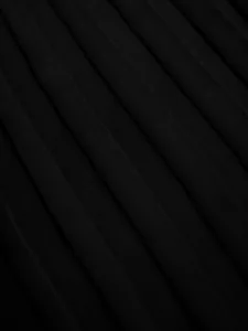 Macro detail of high-quality black pleated fabric showing fine texture and elegant folds