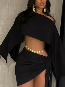 Close-up detail of stylish black one-shoulder crop top and tied mini skirt vacation set