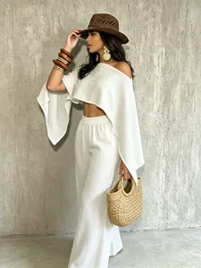 Vista detallada de modelo con crop top blanco asimétrico y pantalones anchos a juego