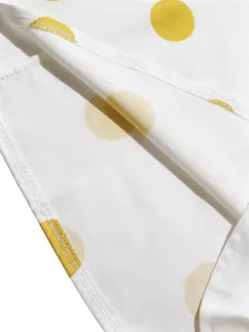 Primer plano detallado de tela blanca con lunares amarillos y costura limpia