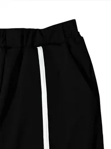 Close-up of black sports pants featuring white side stripe and elastic waistband.