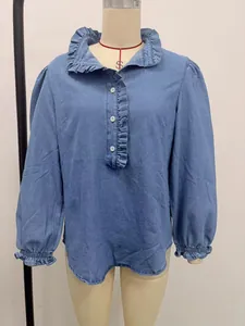 Front view of a light blue denim shirt with ruffle collar and elegant puff sleeves.