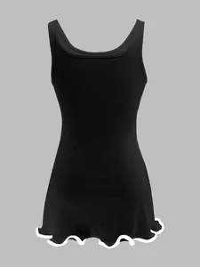 Back view of a black ribbed tank dress featuring a slim fit and ruffled lettuce edge hem.