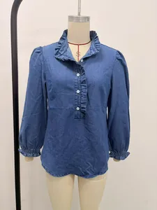 Detailed front view of a blue denim ruffled blouse with puffy sleeves on a mannequin.