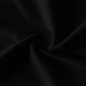 Macro detail shot of soft black ribbed fabric with elegant spiral drape texture.
