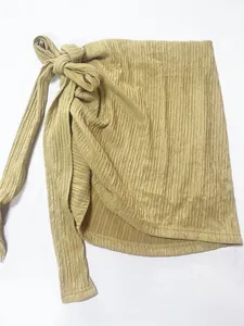 Dettaglio di una minigonna a portafoglio gialla plissettata con fiocco laterale moda