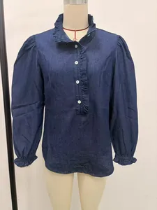 Close-up detail of a blue denim blouse featuring a ruffled collar and puff sleeves
