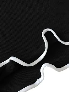Detailed close-up of white wavy lettuce edge trim on black ribbed sleeveless dress fabric