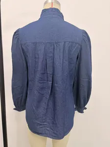 Back view detail of a dark blue denim blouse featuring puff sleeves and ruffle collar.