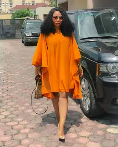 Robe plissée orange grande taille avec manches chauve-souris élégantes portée en extérieur