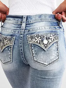 Detailed close-up showing intricate floral embroidery on back pockets of slim denim jeans