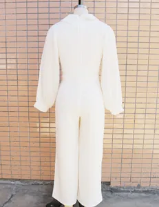 Back view detail of a sophisticated white jumpsuit featuring elegant pleated long sleeves