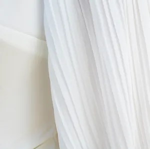Close-up macro view of the delicate white pleated fabric texture on a slim jumpsuit.