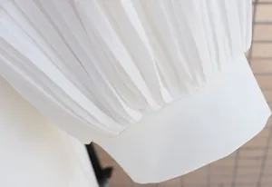 Close-up detail of white pleated sleeve with elegant cuff for women slim fit bodysuit