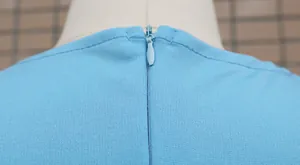 Close-up of the back invisible zipper detail on a light blue slim-fit dress.