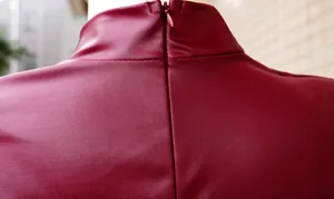 Détail du zip arrière et du col montant sur une robe en similicuir bordeaux élégante.