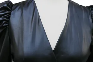 Detailaufnahme des tiefen V-Ausschnitts und der Puffärmel am schwarzen Kunstlederkleid