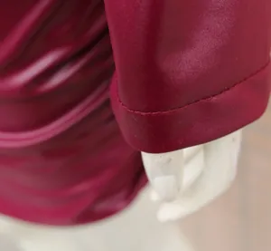Détail du tissu en similicuir bordeaux et des coutures de manches d'une robe
