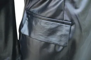 Makro-Detailaufnahme der Taschenklappe und Nähte an einem schwarzen Kunstlederkleid