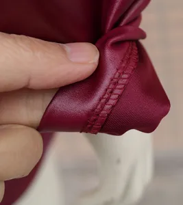 Vue détaillée de la texture du tissu en similicuir bordeaux et des coutures de l'ourlet