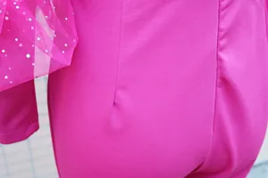 Dettaglio ravvicinato della manica in rete magenta con strass brillanti su una tuta slim