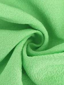 Primer plano detallado de la textura de tela arrugada verde claro con pliegues suaves