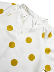 Primer plano del escote en V y el patrón de lunares amarillos en el vestido blanco