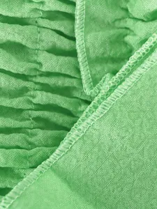 Detalle macro de tela fruncida verde y costura rematada en conjunto de pantalón ancho con volantes