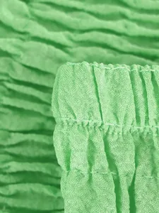 Primer plano detallado de cintura elástica fruncida y tejido verde con textura suave