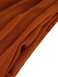Macro detail of burnt orange pleated fabric showing fine crepe texture and elegant drape
