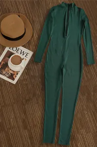 Styled dark green ribbed jumpsuit with zipper detail on a rustic wood background