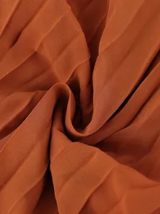 Macro view of burnt orange pleated fabric showing premium texture and elegant draping effect