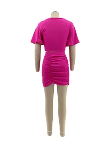 Back view of magenta two-piece set featuring short sleeve crop top and ruched mini skirt