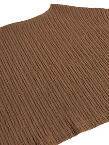 Detailed macro view of the brown vertical pleated textured fabric of the fashion garment.