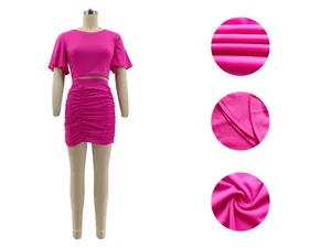 Detail view of vibrant hot pink two-piece set showing fabric texture and ruched skirt seams